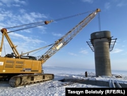 Арнайы техника болашақ көпірдің тіреуін орнатып жатыр. Бұқтырма суқоймасы, Шығыс Қазақстан облысы. 4 ақпан, 2023 жыл