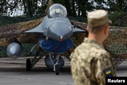 Украинский военнослужащий стоит рядом с одним из первых истребителей F-16, предоставленных союзниками Украине, 4 августа 2024 года