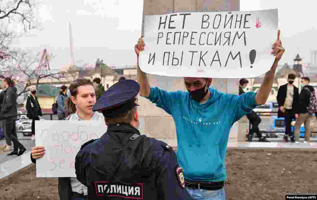 &quot;Соғысқа, қуғын-сүргін мен азаптауға жол жоқ&quot; деген плакат ұстаған оппозиция жақтасымен сөйлесіп тұрған полицей. Владивосток қаласы.&nbsp;