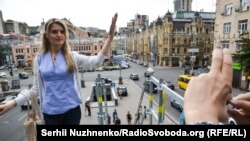 Ленин ескерткіші тұғырында суретке түсіп тұрған бойжеткен. Киев, 9 шілде 2016 жыл.