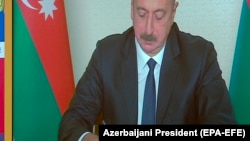 AZERBAIJAN -- Azerbaijani President Ilham Aliyev (R) and Russian President Vladimir Putin sign documents during a video conference call in Baku, November 9, 2020