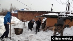 Мүмкіндігі шектеулі адамның үйінің ауласын тазаласып жүрген адамдар. Өскемен, 2 ақпан 2013 жыл. (Көрнекі сурет)