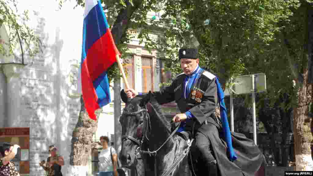 Во главе военно-музыкального шествия ехали несколько человек в казачьей форме на лошадях